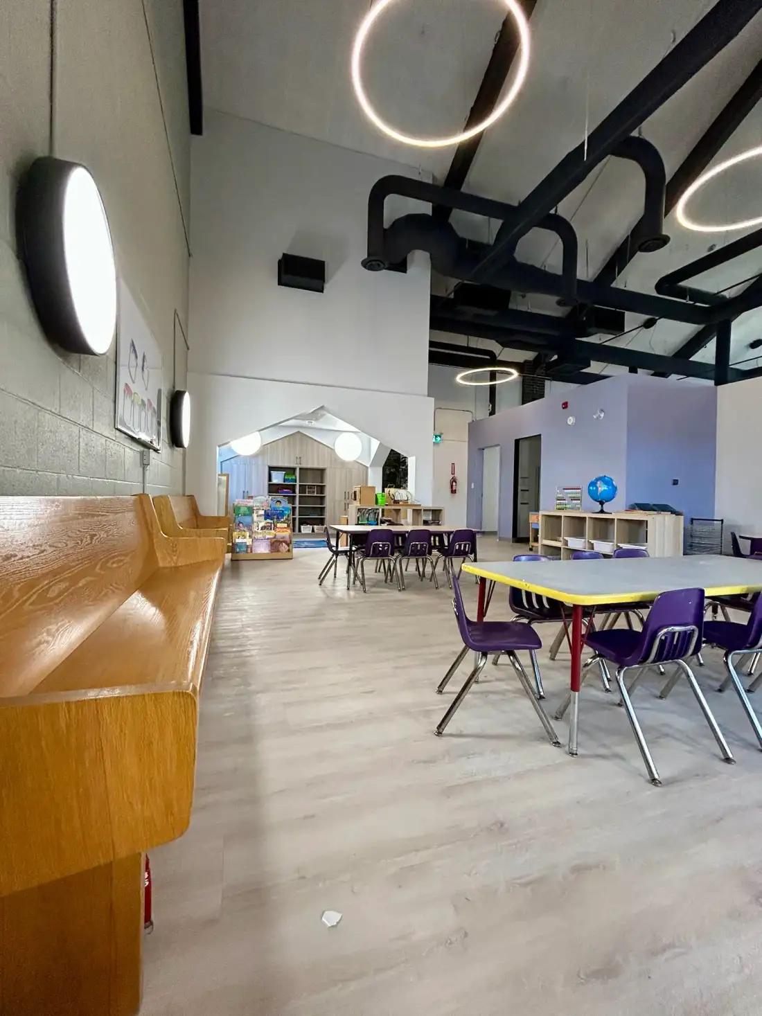 Wide view of interior with wooden bench seating and house-shaped play nook
