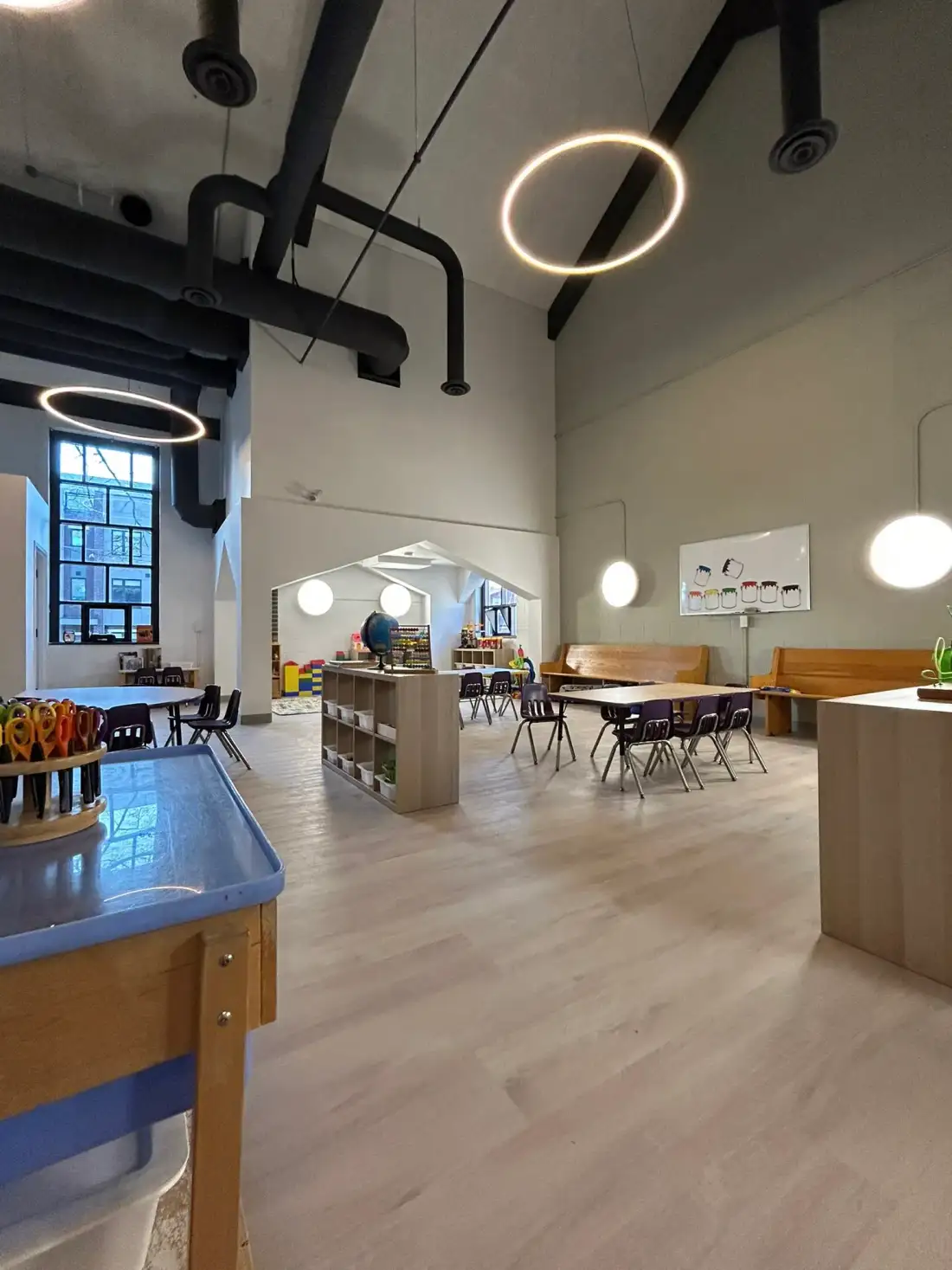 Spacious high-ceiling classroom with sensory table, ring lights, and house-shaped nook
