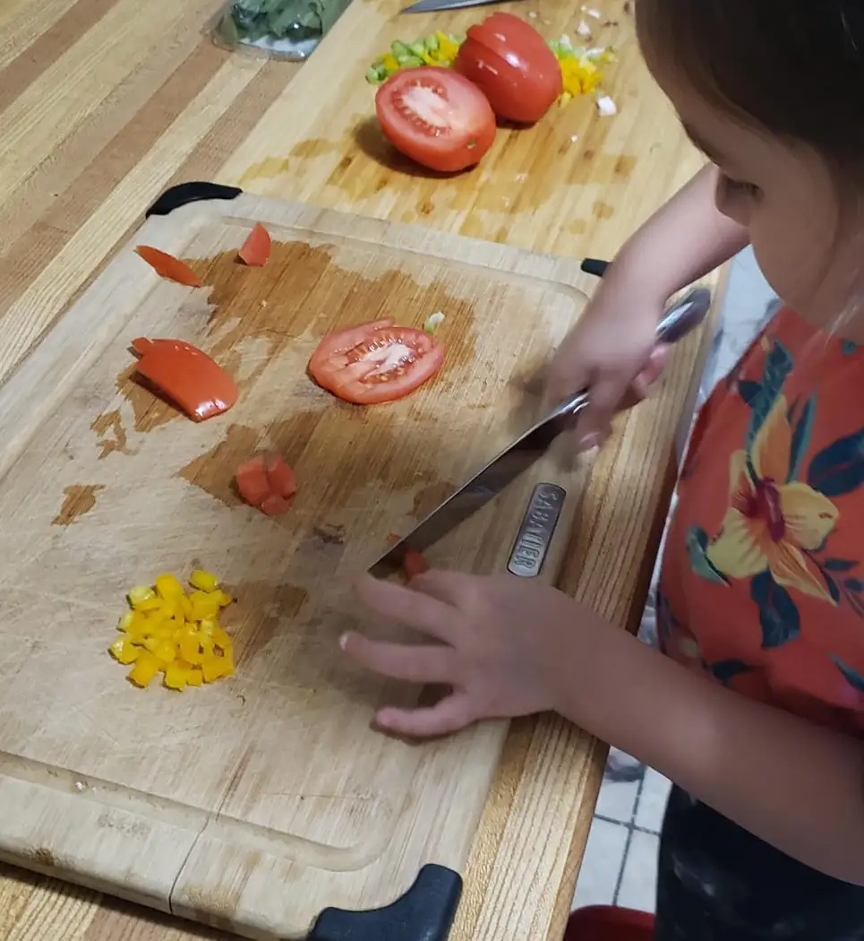 Child chopping tomatoes on a cutting board