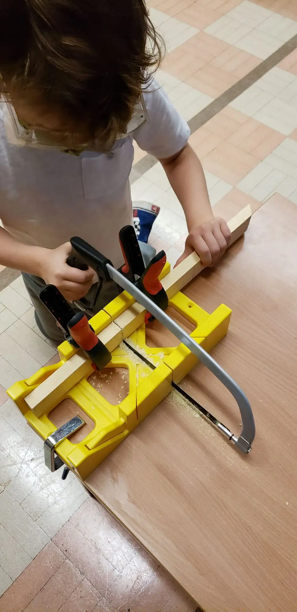 Child sawing wood with a miter box