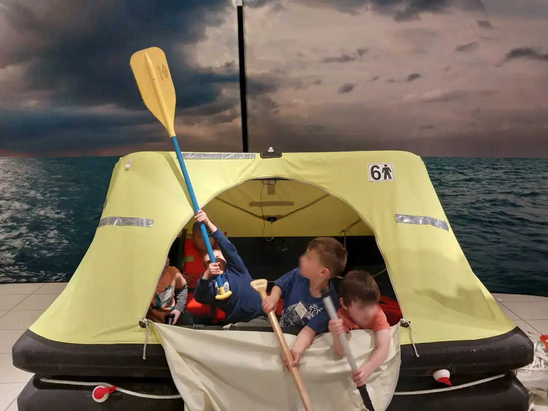 Children in a life raft exhibit with paddles