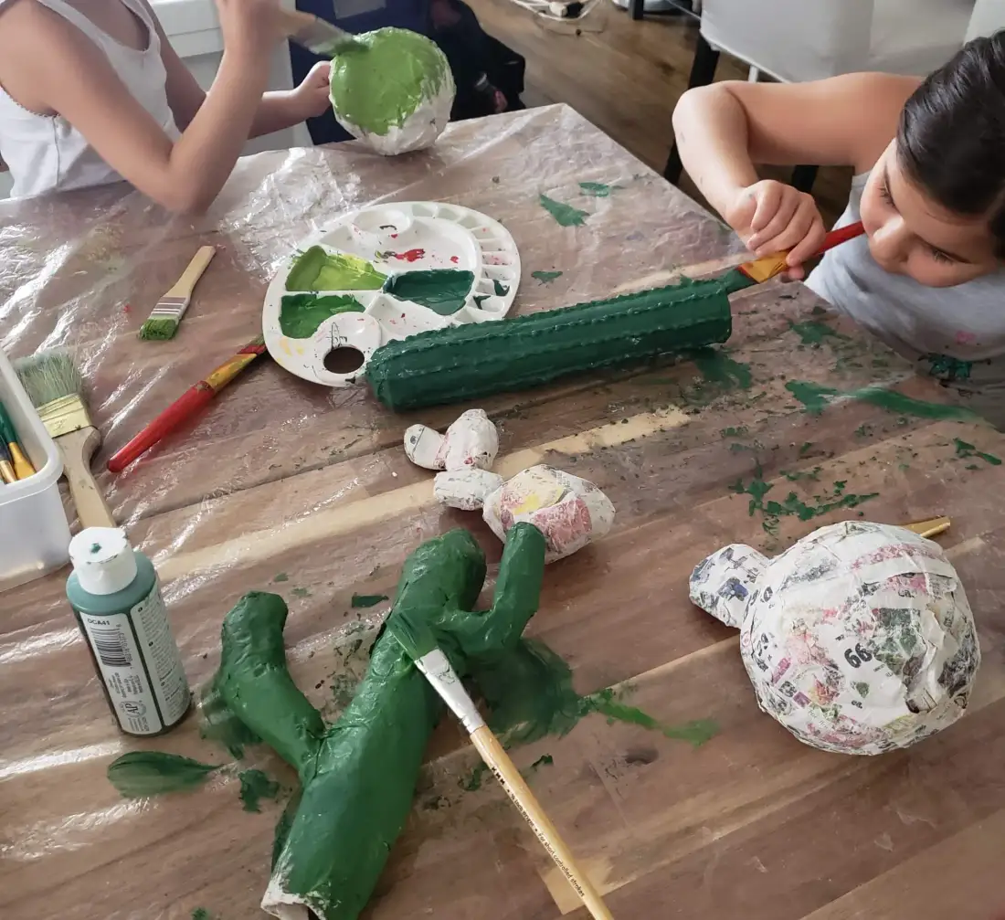 Children painting papier-mache sculptures green