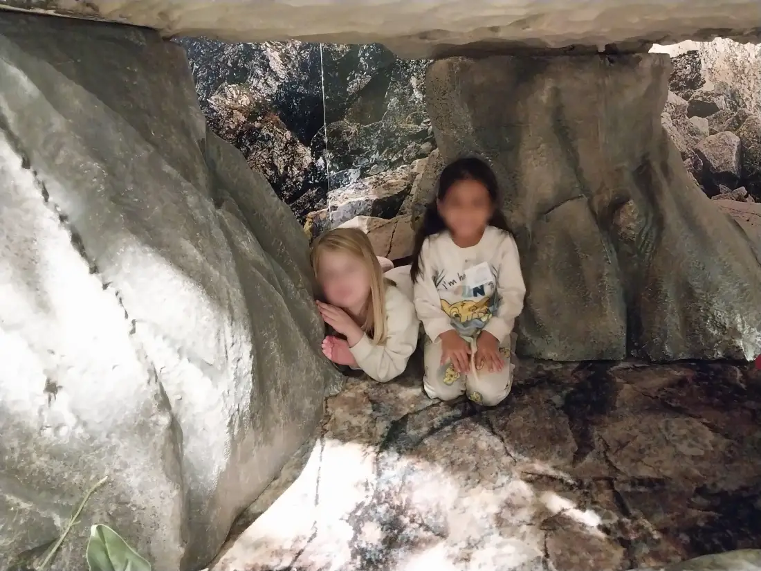 Two children smiling inside a rock cave exhibit